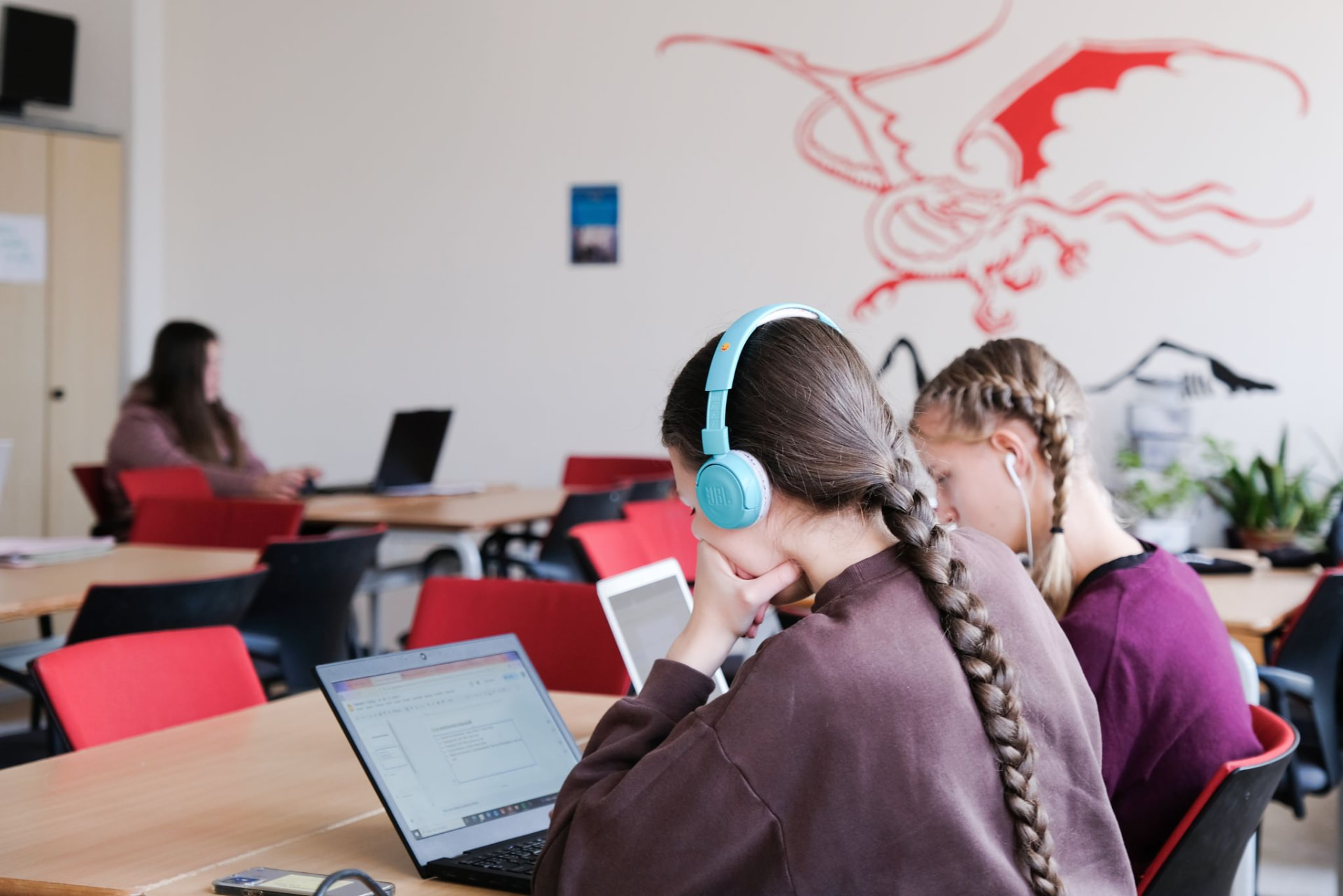 Studentky ScioStřední pracují se sluchátky na notebooku a tabletu ve třídě